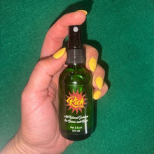 Load image into Gallery viewer, Hand holding a green spray bottle with a brand logo against a green background
